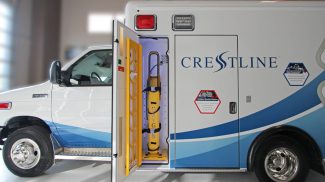 Side view of a Crestline ambulance with an open exterior compartment showing a secured yellow oxygen tank inside