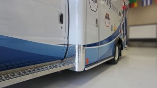Close-up side view of a Crestline ambulance highlighting the blue gradient exterior design, diamond plate side steps, and reinforced lower body trim for durability and safe entry