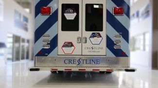 Rear view of a CCL 150 ambulance featuring dual back doors with flush-mount windows, reflective striping, LED tail lights, and a diamond plate bumper with Crestline branding