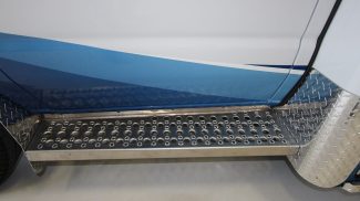 Close-up of a Crestline ambulance side entry step with perforated, non-slip aluminum surface and diamond plate trim for added durability and safety