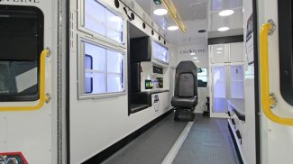 Interior view of a Crestline ambulance, featuring a clean white design with seating, storage cabinets, medical equipment areas, and overhead lighting