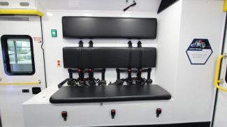 Interior view of an ambulance bench seat with seat belts and padded backrests