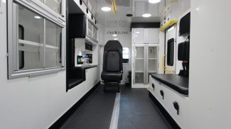 Interior view of a Crestline ambulance, featuring a clean white design with seating, storage cabinets, medical equipment areas, and overhead lighting