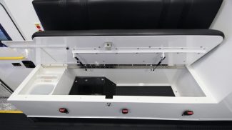 Interior bench seat inside a Crestline ambulance with the cushion lifted to reveal a built-in storage compartment for medical supplies and equipment