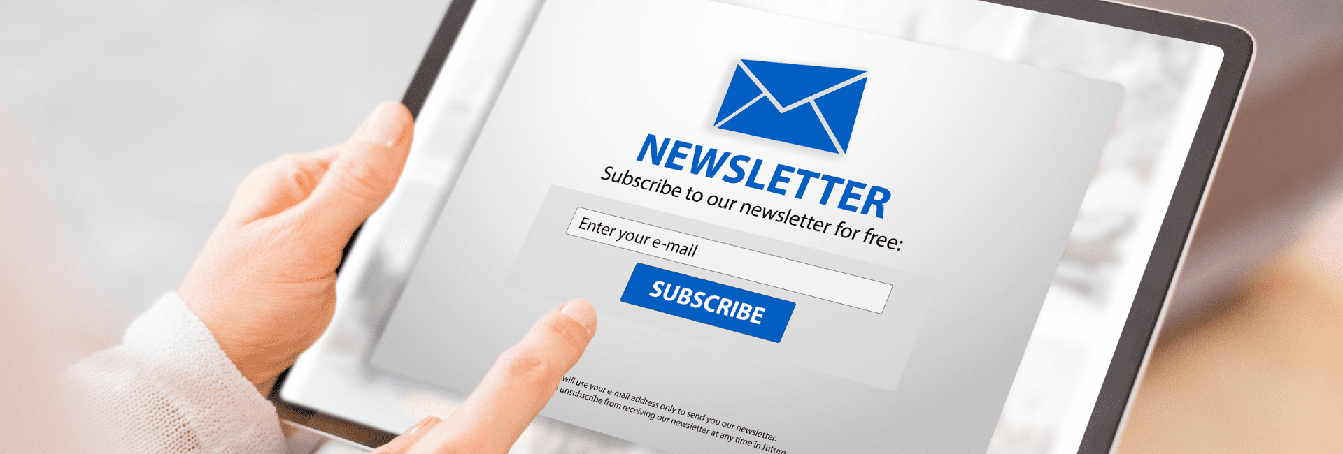 Close-up of a person holding a tablet displaying a newsletter sign-up form with a blue envelope icon, text reading “Subscribe to our newsletter for free,” and a field to enter an email address above a blue “Subscribe” button.