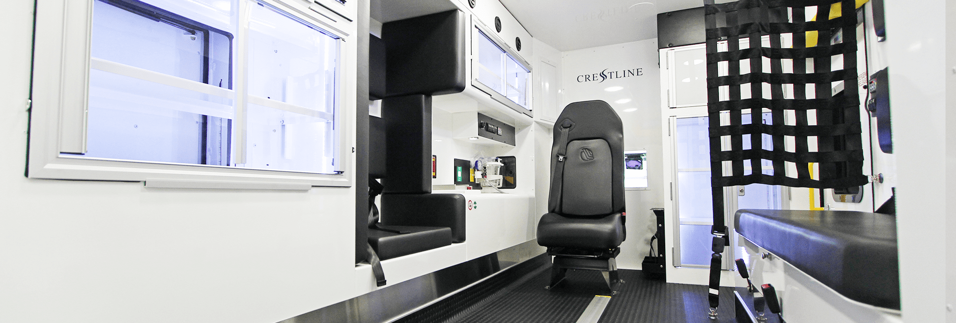 Interior of a Crestline ambulance showing seating, storage compartments, and safety restraints inside the patient care area