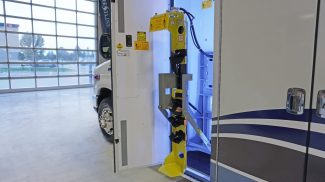 Extended yellow oxygen cylinder lift system mounted inside a Crestline ambulance side compartment, illuminated by interior LED lighting