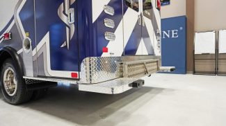 Rear view of a Crestline ambulance highlighting the diamond-plate rear step, LED lighting, and bold blue-and-white Star of Life graphics designed for visibility and durability