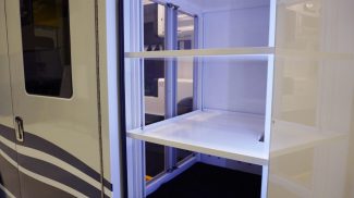 Interior cabinet inside a Crestline ambulance with adjustable white shelving and sliding clear doors, illuminated to showcase organized storage space for medical equipment and supplies