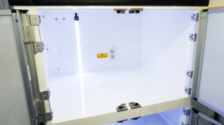 Close-up view of an illuminated interior Crestline ambulance cabinet with white shelving, clear doors, and built-in electrical outlets