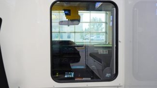 View through the pass-through window from the patient compartment into the cab of a Crestline ambulance, showing the dashboard, rearview mirror, and control console