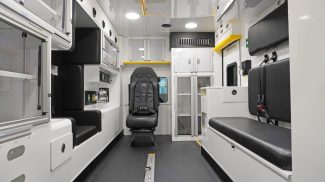 Interior view of a Crestline ambulance showing a clean, organized layout with seating for crew members, overhead storage cabinets, medical equipment compartments, and durable anti-slip flooring designed for safety and efficient patient care