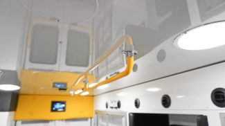 Ceiling-mounted yellow grab rail extending the length of the Crestline ambulance interior, providing stability for EMS personnel during patient transport