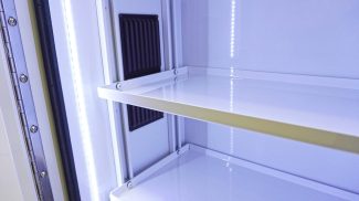 Interior view of an illuminated Crestline ambulance storage cabinet showing smooth white shelving, LED lighting strips, and a black ventilation panel on the back wall