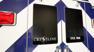 Close-up of the rear doors on a Crestline CCL 166 ambulance featuring blue and white chevron graphics, tinted windows, and chrome door handles