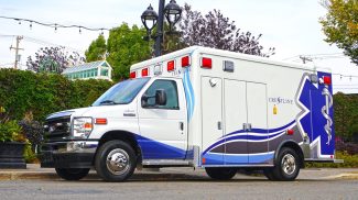 Crestline CCL 166 ambulance parked on a city street, highlighting its modern blue and white design with reflective graphics and safety lighting