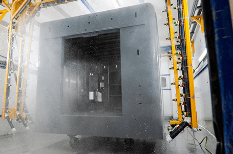 Crestline ambulance module in a paint booth, with automated sprayers applying protective coating to the exterior