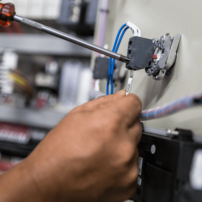 Close-up of a technician’s hand using a screwdriver to connect electrical wiring inside a Crestline ambulance during the assembly process