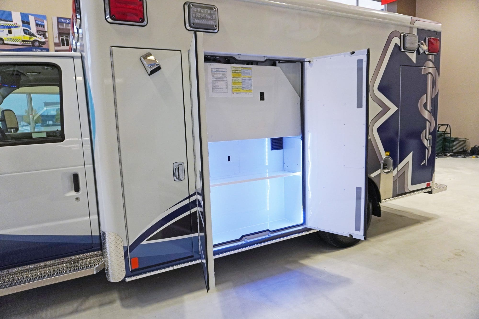 Side compartment of a Crestline ambulance shown open, revealing illuminated shelving and a clean, organized storage space