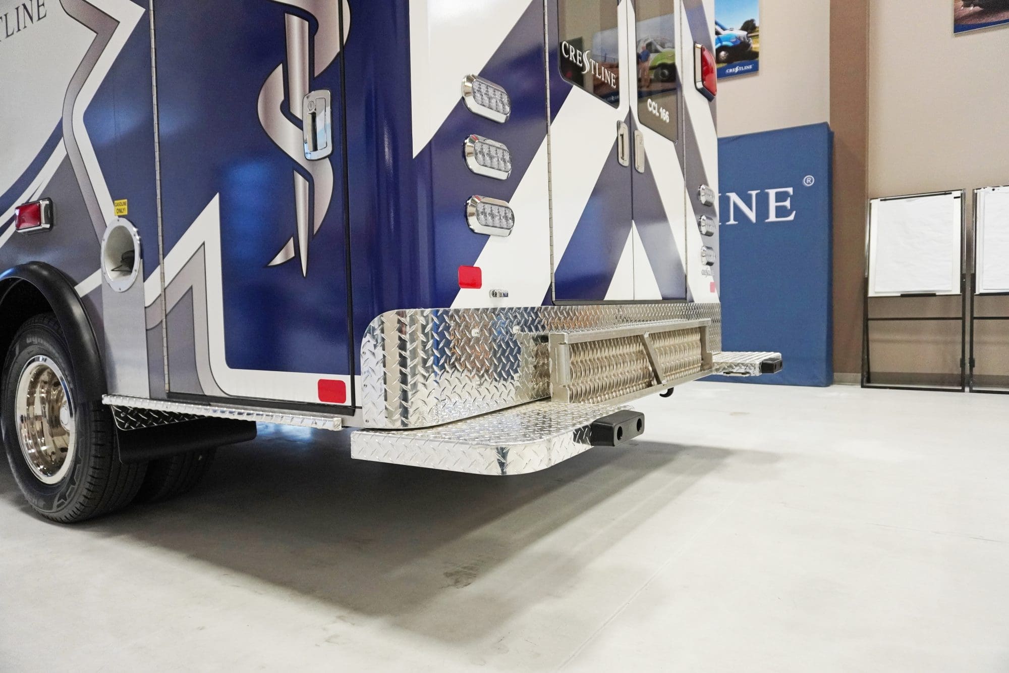 Rear view of a Crestline ambulance highlighting the diamond-plate rear step, LED lighting, and bold blue-and-white Star of Life graphics designed for visibility and durability