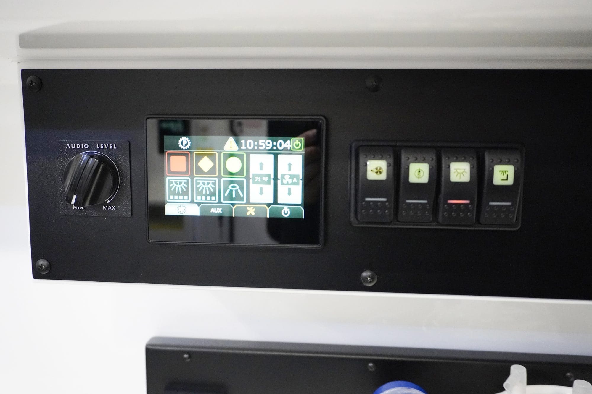 Close-up view of a Crestline ambulance control panel featuring a digital touchscreen interface for lighting and temperature settings, illuminated rocker switches, and an audio level dial