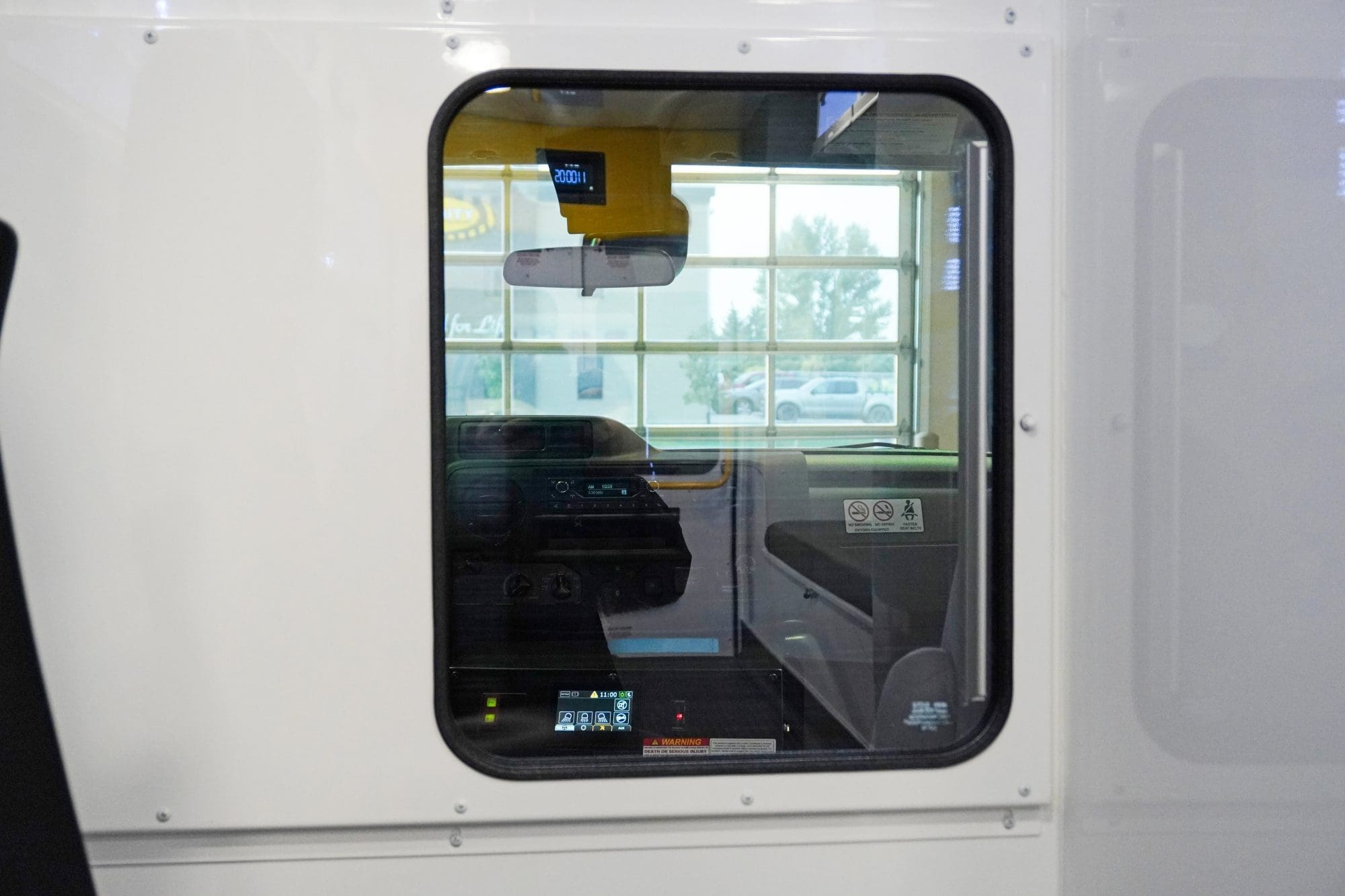 View through the pass-through window from the patient compartment into the cab of a Crestline ambulance, showing the dashboard, rearview mirror, and control console