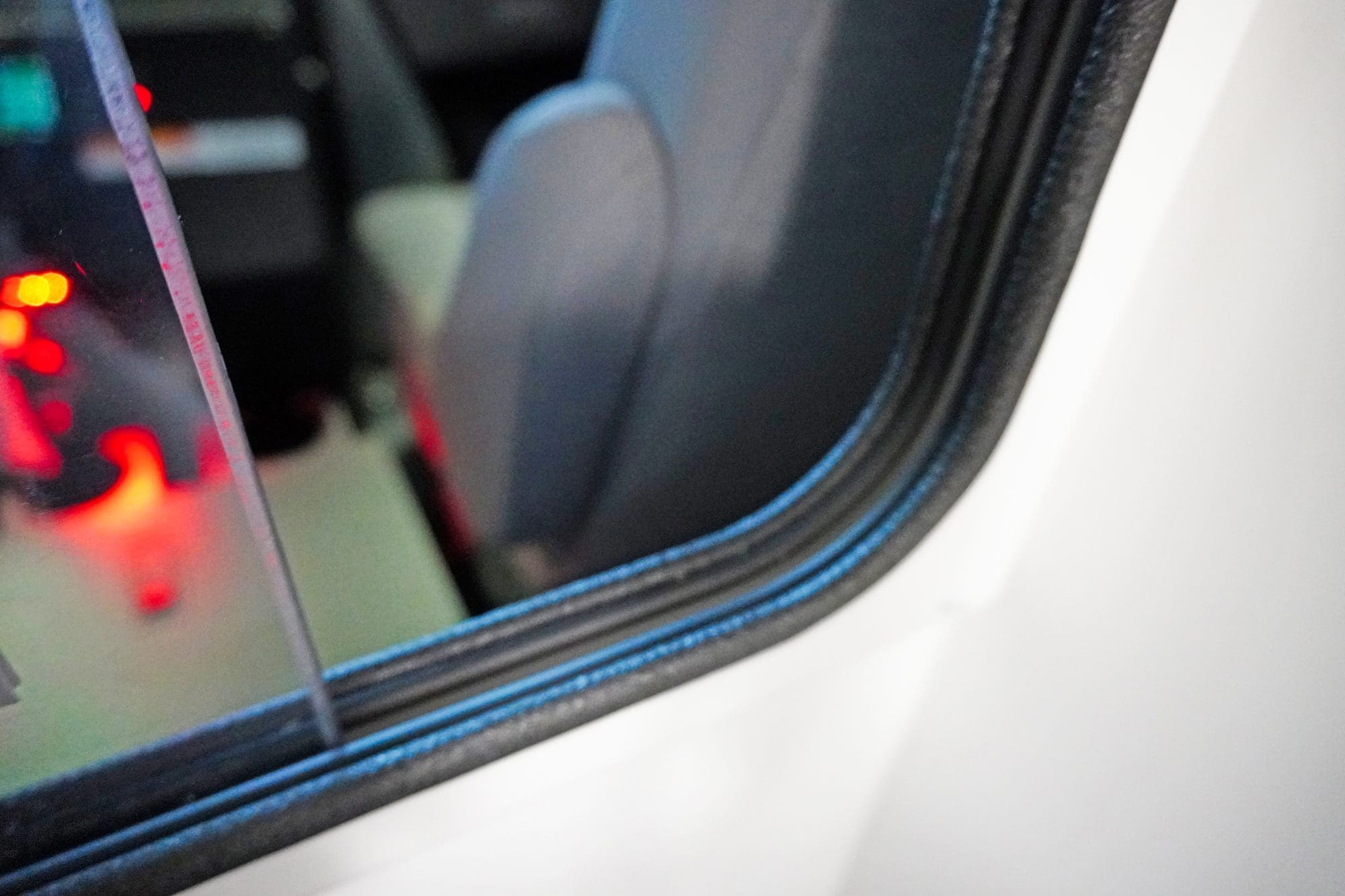 Close-up view through the pass-through window between the cab and patient compartment of a Crestline ambulance, showing part of the seat and illuminated console area with red lighting