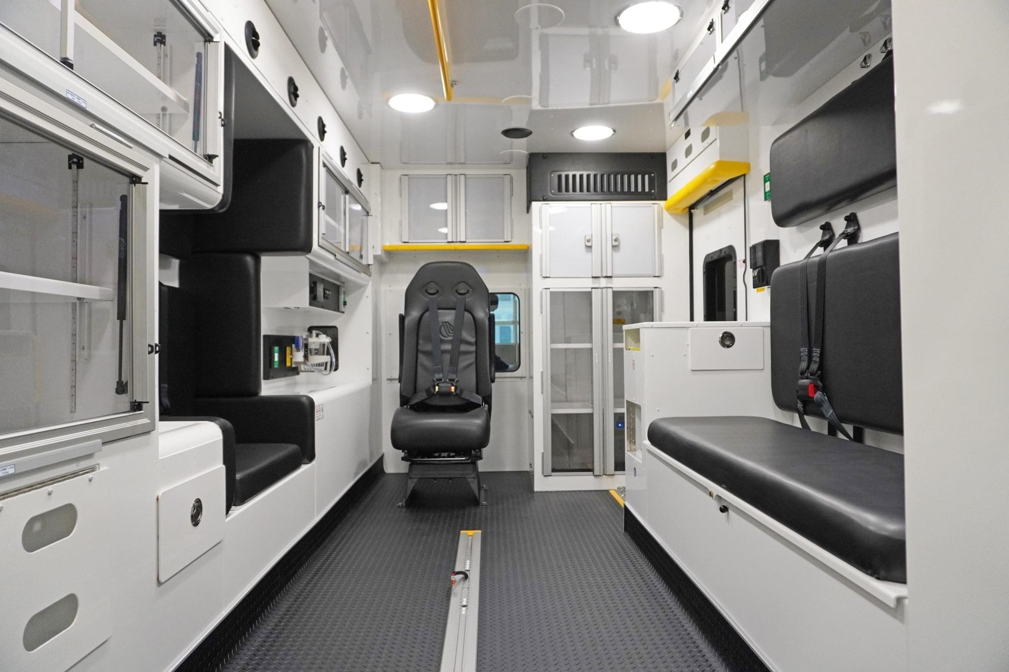 Interior view of a Crestline ambulance showing a clean, organized layout with seating for crew members, overhead storage cabinets, medical equipment compartments, and durable anti-slip flooring designed for safety and efficient patient care