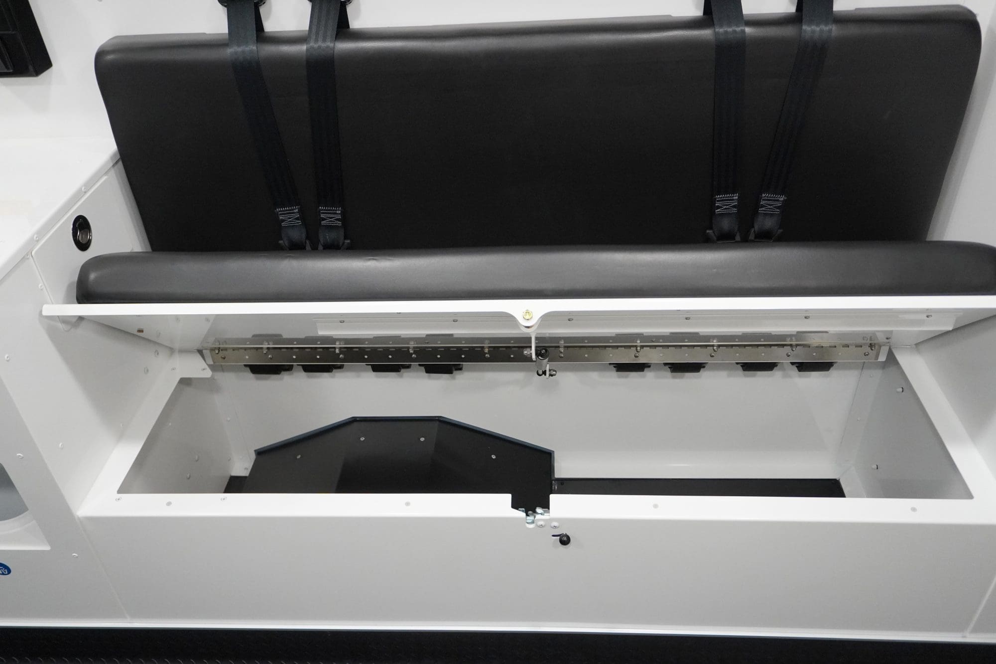 Under-seat storage compartment inside a Crestline ambulance with the bench seat lifted, showing accessible space for securing medical equipment or supplies