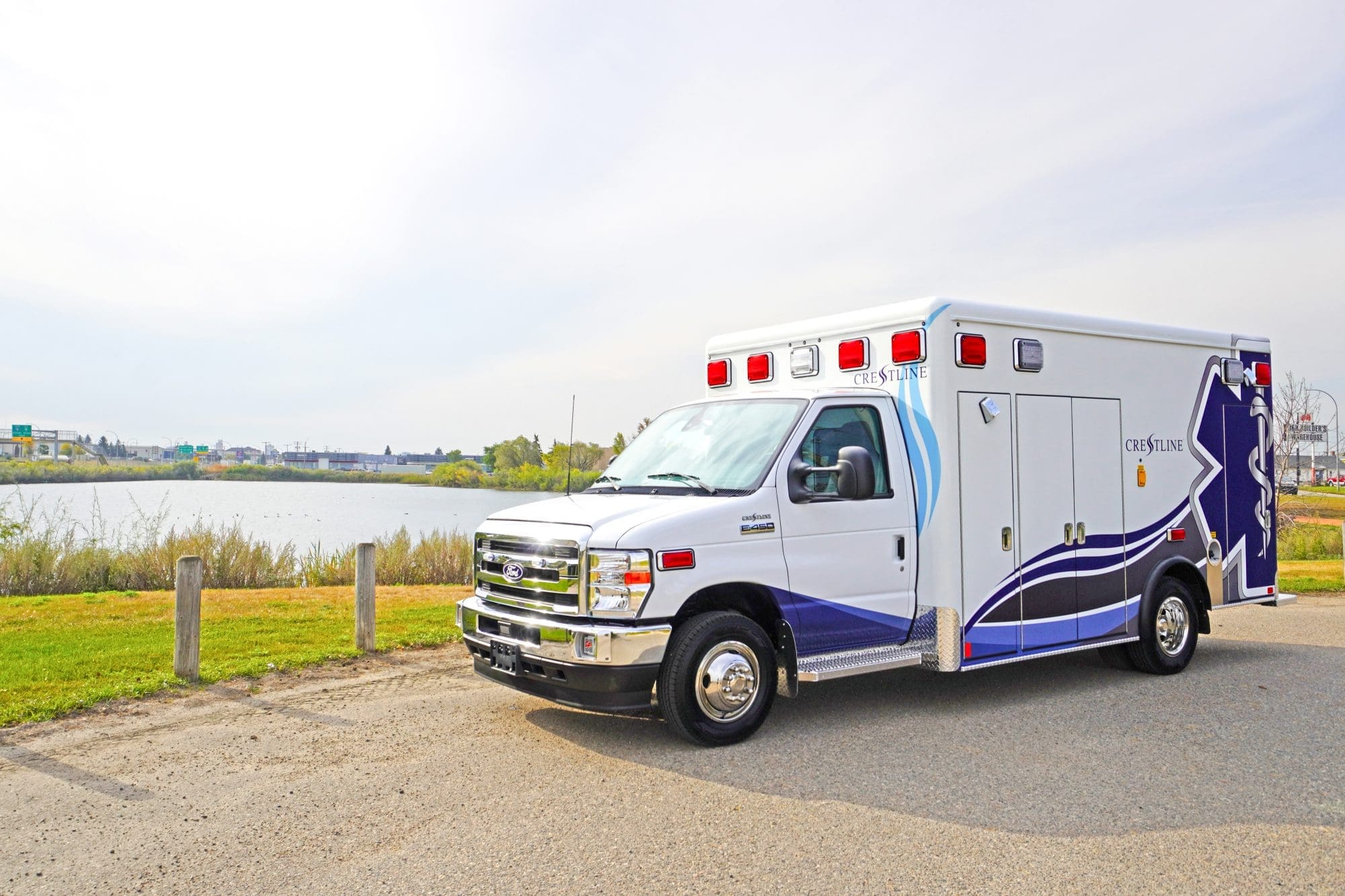 Crestline CCL 166 ambulance parked beside a river under a bright sky, showcasing its clean design and reflective graphics