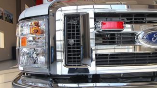 Close-up of the front grille and headlight assembly on a Crestline ambulance, featuring a Ford chassis with chrome accents and integrated emergency lighting